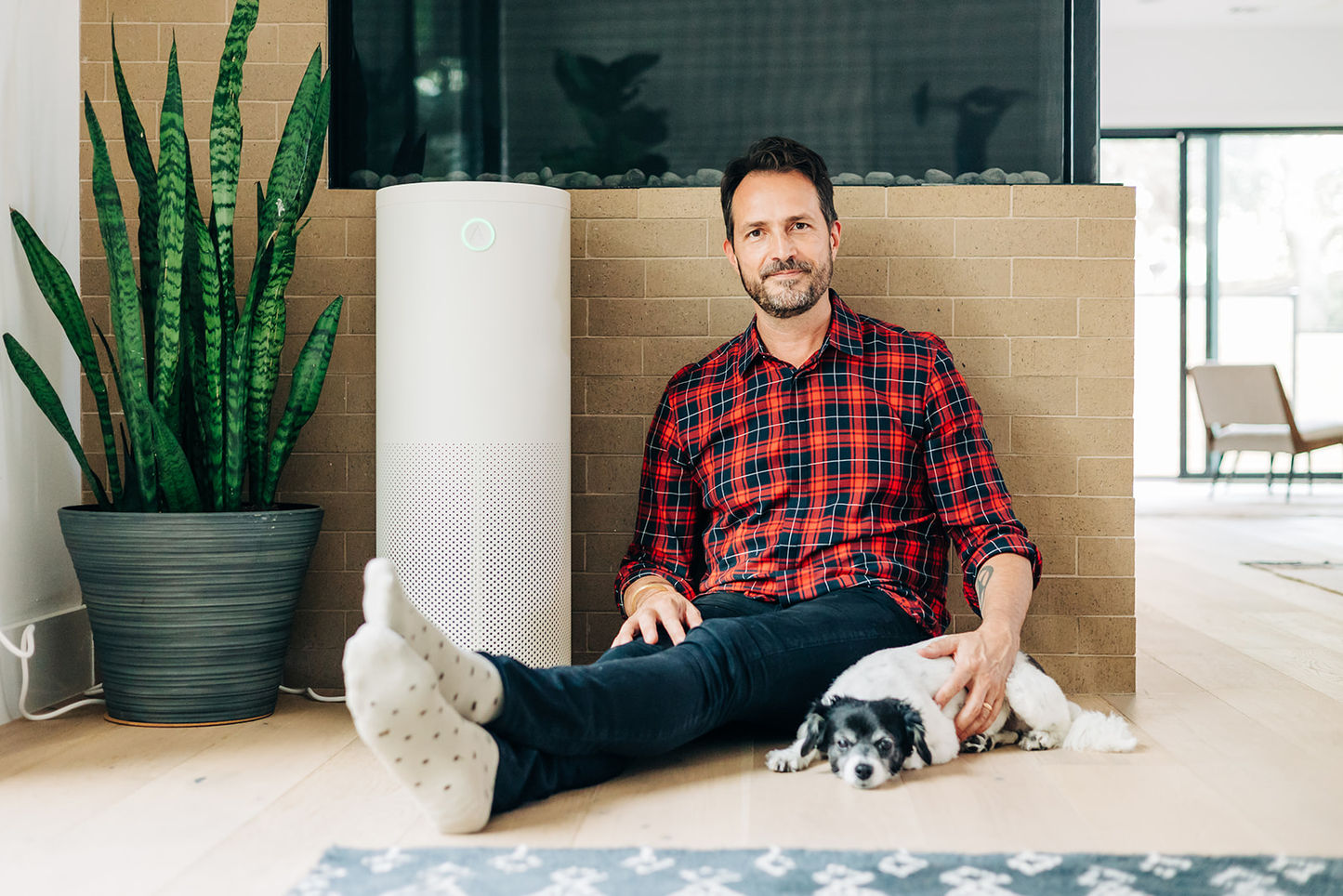 Man sitting on floor with his dog inside against a wall beside a Jaspr